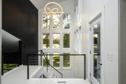The staircase is a central design feature of this home, with a large glass wall looking out over the water and an exposed stair providing an architectural feature just after walking in the front door.